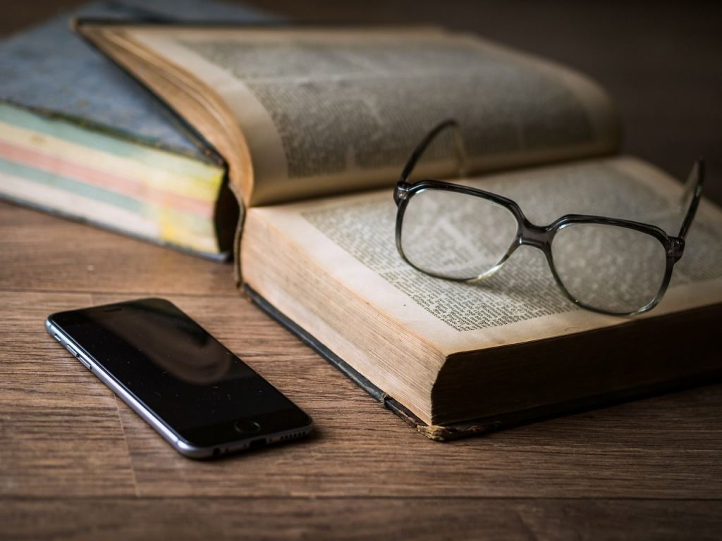 Glasögon ligger på bok bredvid smartphone